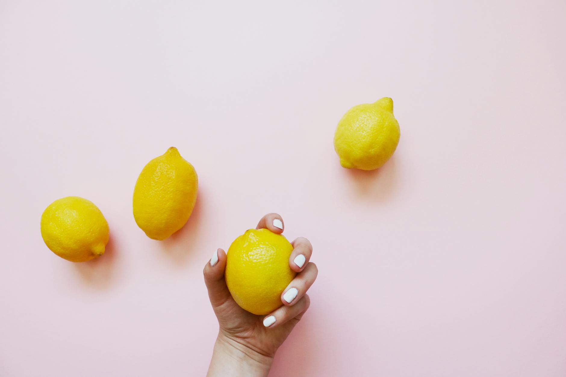 A hand holding a fresh lemon on soft pink background, representing the approach to desire mismatch with intentionality and care