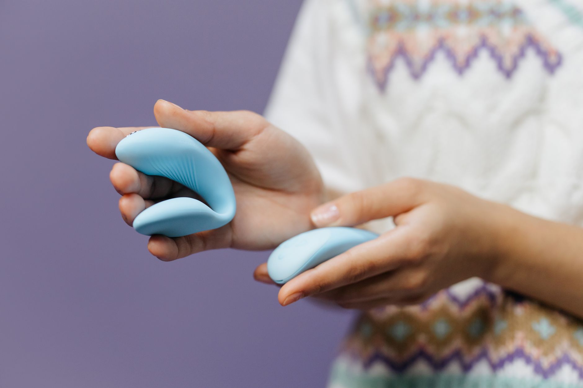 Hands holding a sleek lemon vibrator against a purple background, symbolizing nervous system recovery and pleasure