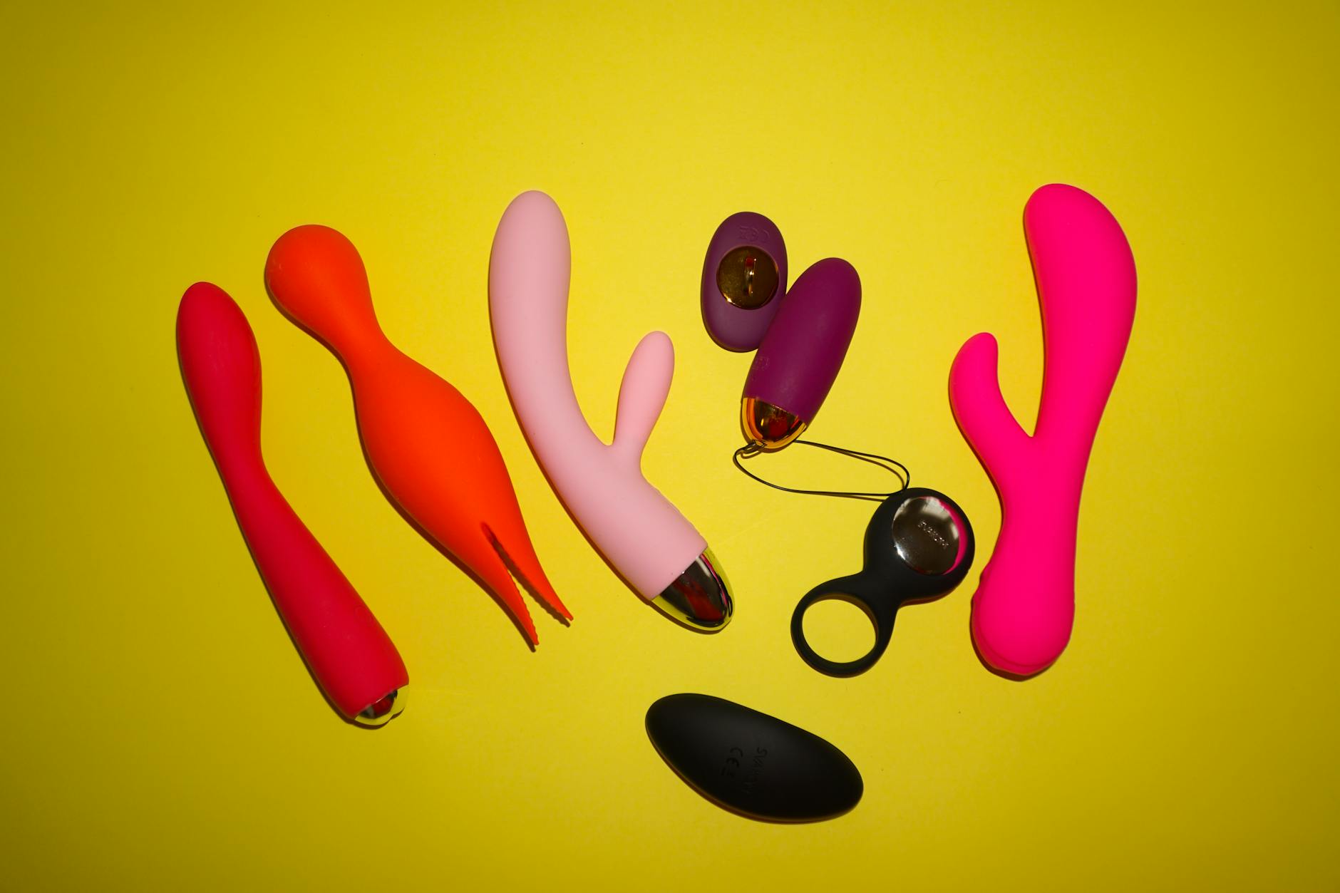 Teal clitoral vibrator on white silk fabric, representing accessible pleasure for people with penetration pain